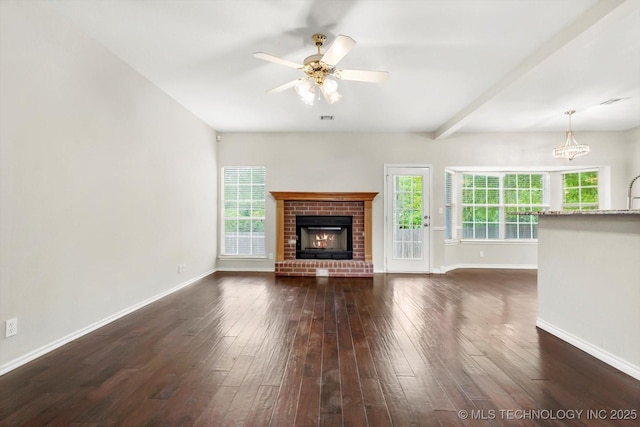unfurnished living room featuring a fireplace, ceiling fan with notable chandelier, baseboards, dark wood-type flooring, and visible vents