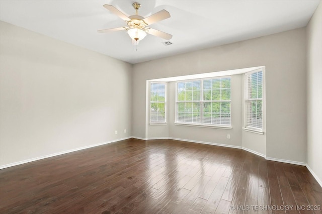unfurnished room with baseboards, a ceiling fan, dark wood-style floors, and visible vents