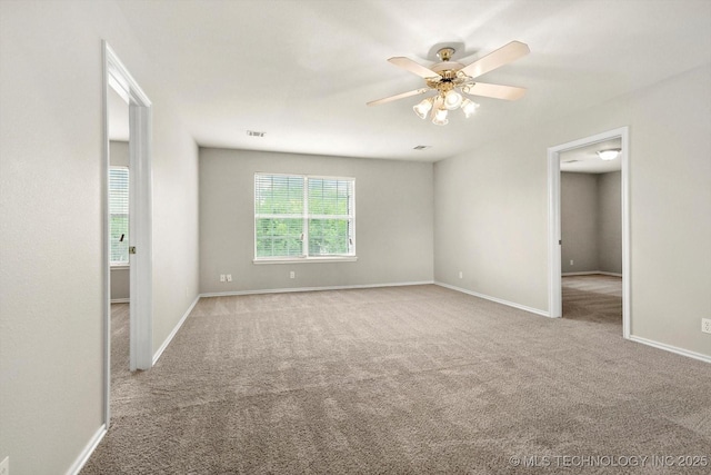 carpeted empty room with a ceiling fan, baseboards, and visible vents