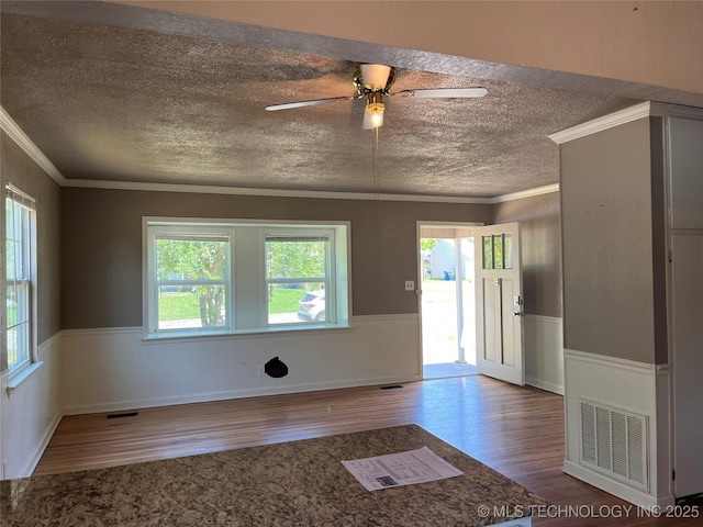 304 E 45th Ct, Tulsa, OK 74105 - empty room with wood finished floors, a textured ceiling, ornamental molding, plenty of natural light, and a wainscoted wall