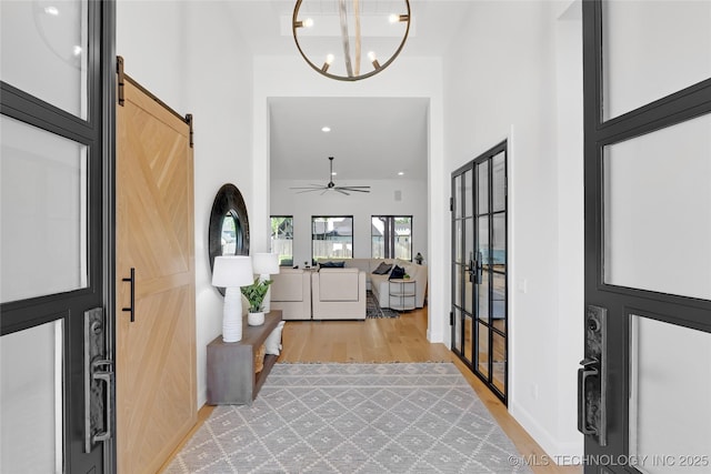 foyer entrance with a towering ceiling, recessed lighting, washer and clothes dryer, a barn door, and light wood-style flooring