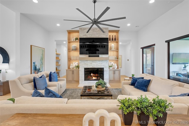 living room featuring a ceiling fan, recessed lighting, light wood-type flooring, and a fireplace