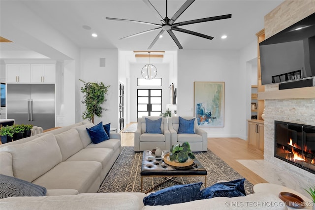 living room featuring baseboards, ceiling fan, light wood-type flooring, recessed lighting, and a large fireplace