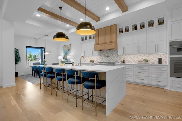 kitchen with light wood-style flooring, backsplash, beam ceiling, and stainless steel appliances