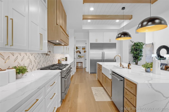 kitchen featuring backsplash, high end appliances, beam ceiling, a sink, and light wood-style flooring