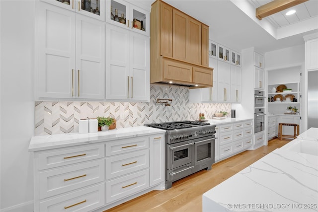 kitchen featuring decorative backsplash, light stone countertops, white cabinets, light wood finished floors, and stainless steel appliances