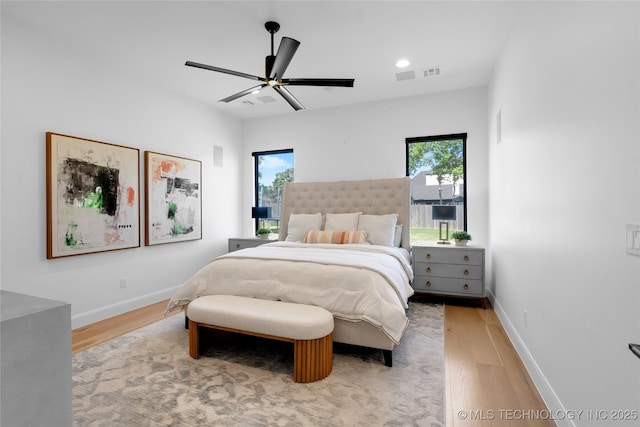 bedroom with light wood-style floors, a ceiling fan, baseboards, and visible vents