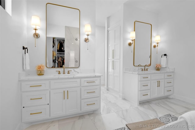 bathroom featuring baseboards, a sink, marble finish floor, and two vanities