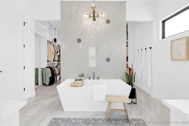 full bath with a chandelier, a freestanding bath, and marble finish floor