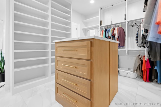 walk in closet featuring marble finish floor