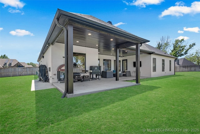 back of property featuring ceiling fan, stucco siding, a fenced backyard, an outdoor living space, and a yard