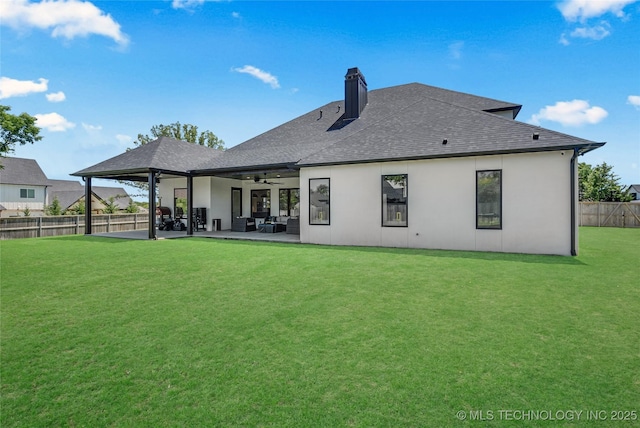 back of property with ceiling fan, a chimney, a lawn, a patio area, and a fenced backyard