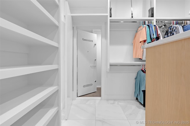 walk in closet with marble finish floor