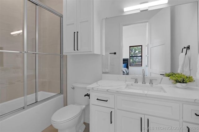 bathroom with toilet, enclosed tub / shower combo, and vanity