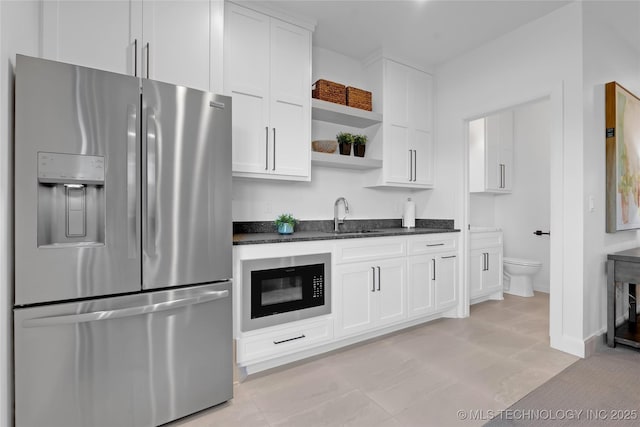 kitchen with stainless steel refrigerator with ice dispenser, black microwave, open shelves, a sink, and white cabinets