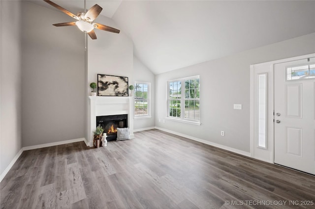 unfurnished living room with a glass covered fireplace, high vaulted ceiling, a ceiling fan, and wood finished floors