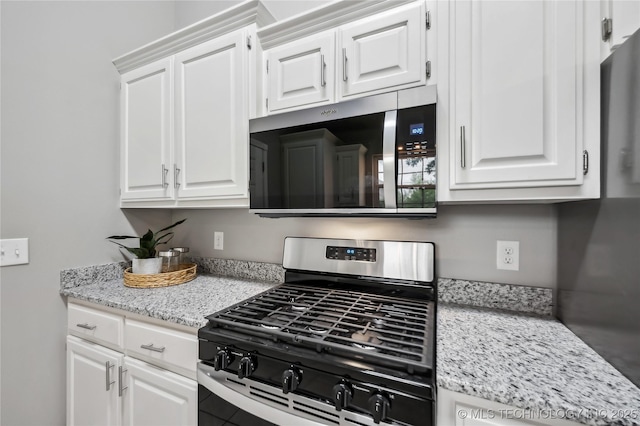 kitchen featuring appliances with stainless steel finishes, light stone counters, and white cabinetry