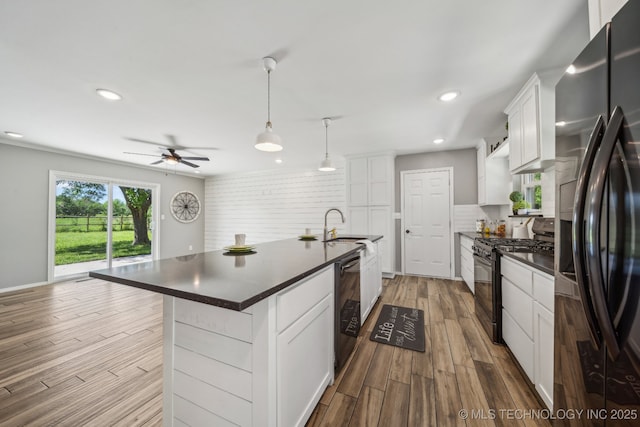 kitchen featuring dark countertops, black range with gas stovetop, dark wood-type flooring, fridge with ice dispenser, and a sink