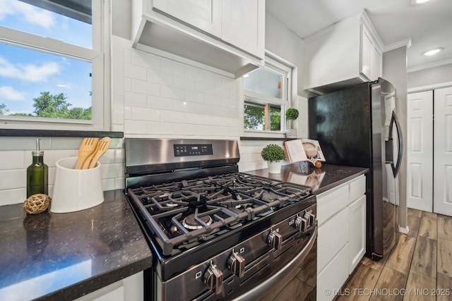 kitchen with white cabinets, stainless steel appliances, ornamental molding, and tasteful backsplash