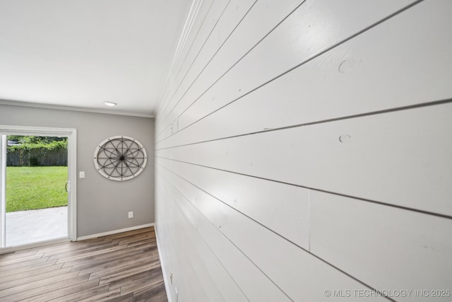 interior space featuring wooden walls, baseboards, ornamental molding, and wood finished floors