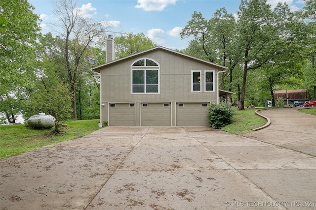 view of property exterior featuring concrete driveway, a yard, a chimney, and a garage