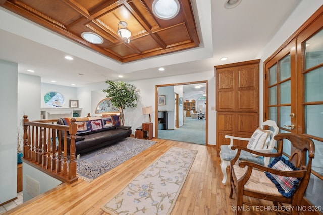 interior space featuring recessed lighting, a raised ceiling, coffered ceiling, and light wood-type flooring