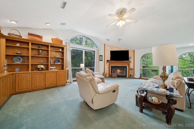 living area with visible vents, ceiling fan, light colored carpet, a large fireplace, and vaulted ceiling