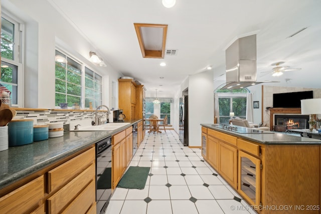 kitchen featuring dark countertops, a sink, island range hood, visible vents, and black appliances