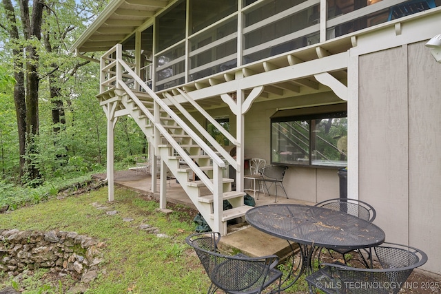 view of patio / terrace featuring stairs, a sunroom, and outdoor dining space
