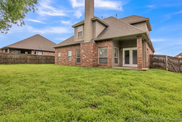 rear view of house with a fenced backyard, a chimney, a lawn, and brick siding
