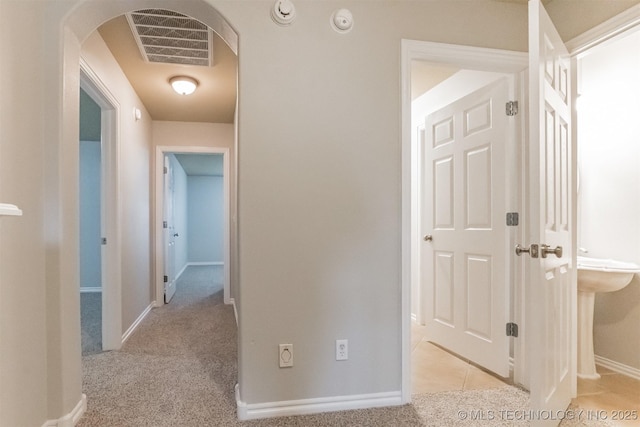 hall with visible vents, arched walkways, baseboards, and carpet flooring