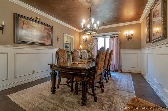 11615 S New Haven Ave, Tulsa, OK 74137 - dining room featuring a notable chandelier, wainscoting, a decorative wall, wood finished floors, and ornamental molding