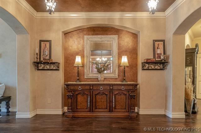 11615 S New Haven Ave, Tulsa, OK 74137 - hall with baseboards, arched walkways, dark wood finished floors, and a chandelier