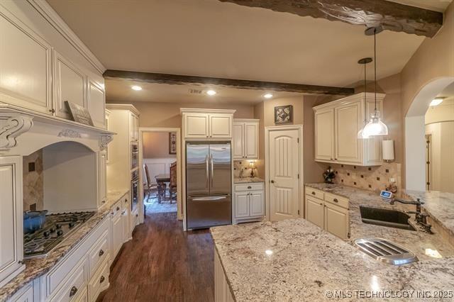 11615 S New Haven Ave, Tulsa, OK 74137 - kitchen featuring appliances with stainless steel finishes, arched walkways, dark wood finished floors, a sink, and beamed ceiling