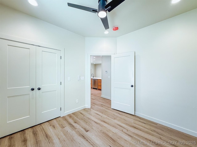 unfurnished bedroom featuring baseboards, a closet, recessed lighting, and light wood-style flooring