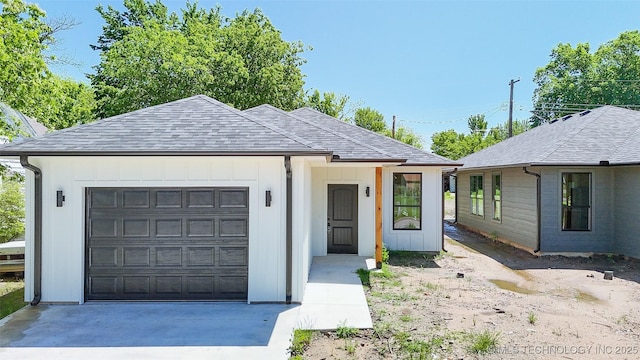ranch-style home with board and batten siding, driveway, roof with shingles, and a garage