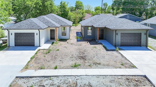 ranch-style house featuring concrete driveway, an attached garage, and roof with shingles
