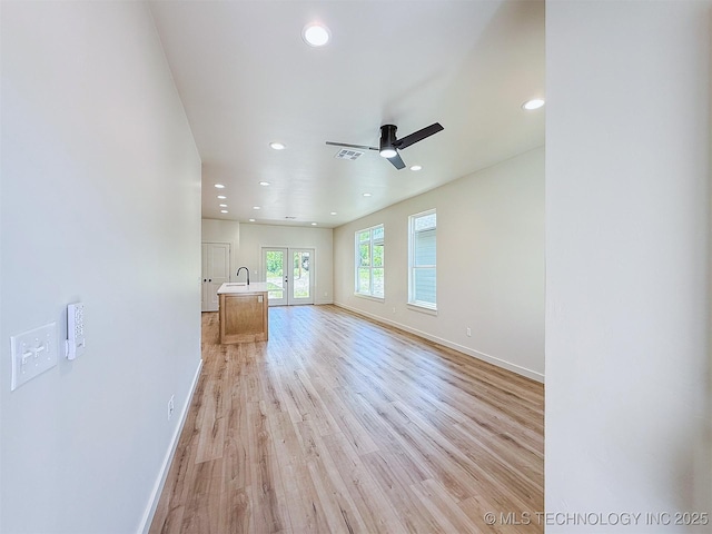 unfurnished living room featuring a ceiling fan, baseboards, recessed lighting, and light wood-type flooring