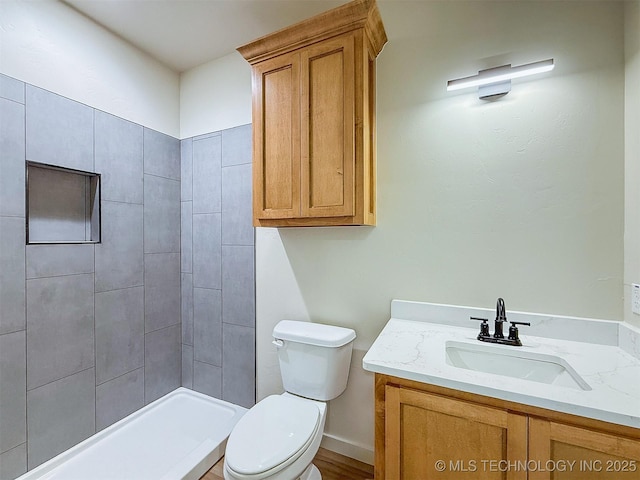full bathroom with vanity, a tile shower, and toilet