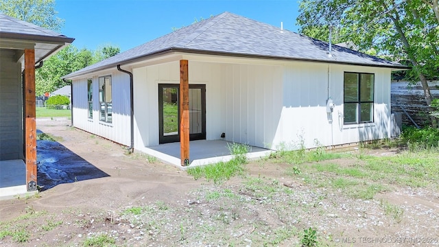 rear view of house featuring a patio and a shingled roof