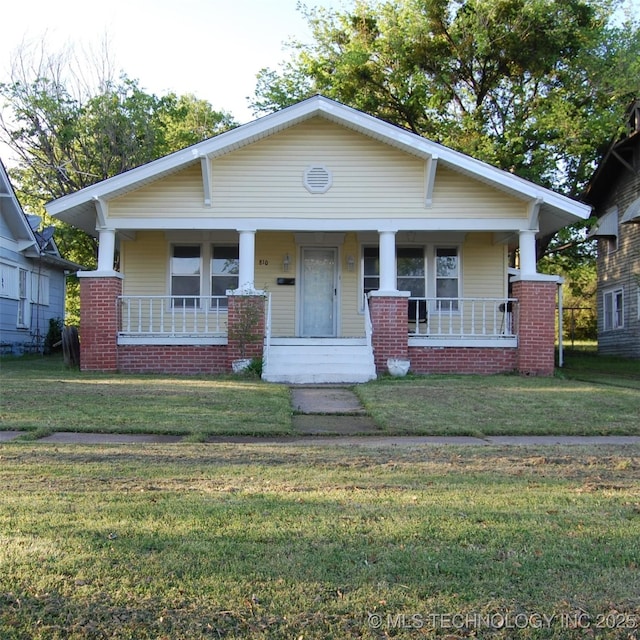 bungalow-style home featuring covered porch and a front yard