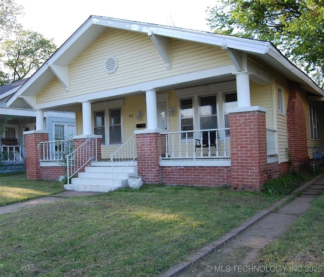 view of front facade with brick siding, covered porch, and a front yard
