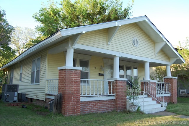 bungalow-style home featuring a porch, central AC, and brick siding