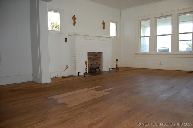 unfurnished living room featuring ornamental molding, wood finished floors, and a fireplace