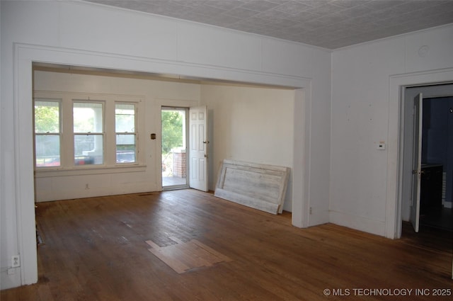 unfurnished room with ornamental molding and wood finished floors