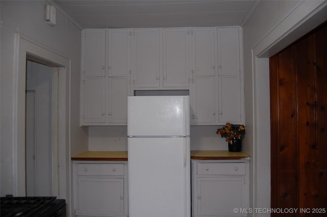 kitchen with freestanding refrigerator, white cabinetry, and light countertops