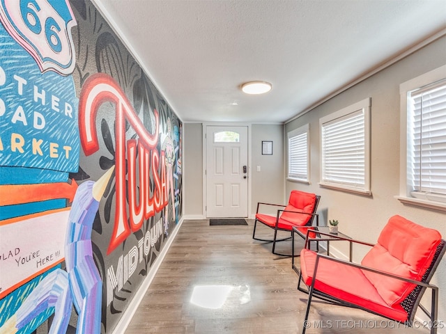 foyer featuring baseboards, a textured ceiling, and wood finished floors