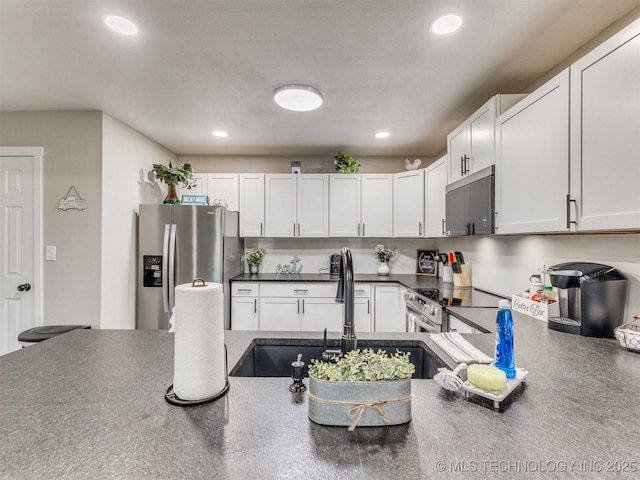 kitchen with recessed lighting, a sink, dark countertops, and stainless steel appliances
