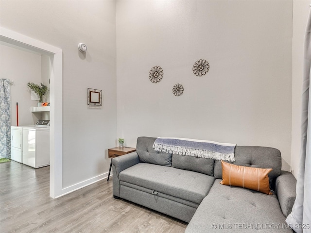 living area with light wood-style floors, baseboards, and washer and dryer