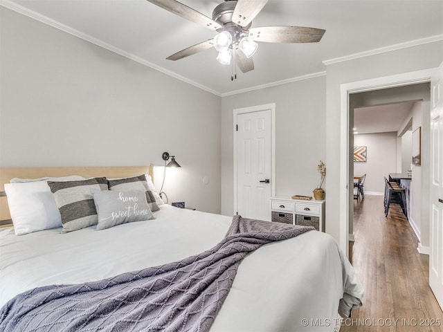 bedroom with baseboards, ornamental molding, a ceiling fan, and wood finished floors